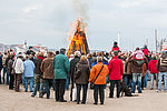 Menschen stehen um ein Osterfeuer an der Flensburger Förde. 