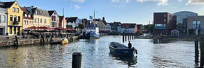 Ein kleines Boot fährt durch den Binnenhafen von Husum.  - zum Artikel 'Schleswig-Holstein-Tourismus im November 2021: Nebensaison gewinnt an Bedeutung – Bilanz nach elf Monaten'