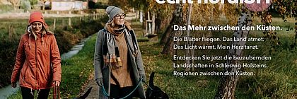Kampagnen Motiv Echt Nordish: Zwei Frauen gehen mit ihren Hunden in hersbtlicher Umgebung spazieren. Auf dem Bild ist ein Text zum Herbst im Binnenland zu lesen. - zum Artikel '„echt nordiSH – Das Mehr zwischen den Küsten“: Schleswig-Holsteins Binnenregionen starten erste gemeinsame Tourismuskampagne'