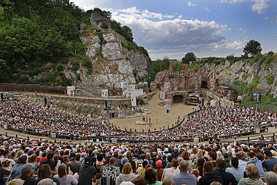Viele Zuschauer sitzen auf der Tribüne am Kalkberg und schauen auf die Karl-May-Spiele im Schleswig-Holstein Urlaub.