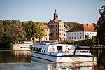 Die MS Freischütz fährt über den Großen Eutiner See. Im Hintergrund befindet sich das Eutiner Schloss.