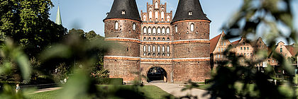 Lübecker Holstentor bei blauem Himmel.  - zum Artikel 'Schleswig-Holsteins Welterbe hautnah erleben - Sonntag, 04. Juni, ist UNESCO-Welterbetag'