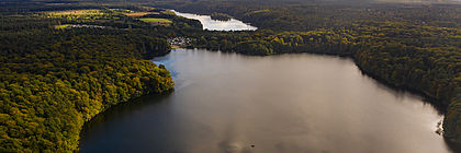 Luftaufnahme des Lütauer Sees umgeben von Wald.  - zum Artikel 'Buchungslage im Schleswig-Holstein-Tourismus für Pfingsten und Ausblick auf den Sommer 2023'