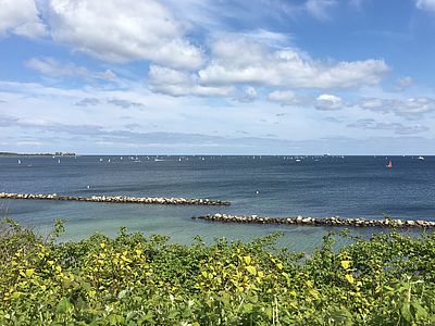 Ausblick auf den Strand in Kiel-Schilksee, auf der Ostsee sind zahlreiche Segelboote unterwegs.