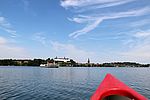 Ein rotes Kajak schwimmt auf dem großen Plöner See. Im Hintergrund befindet sich das Plöner Schloss.