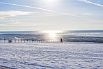 Verschneiter und Vereister Nordseestrand. Die Sonne spiegelt sich im Meer.