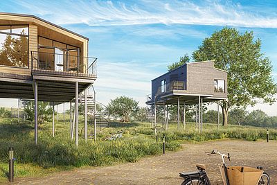 Zwei moderne Stelzenhäuser mit Balkonen in grüner Natur, erreichbar über Wendeltreppen, davor ein Lastenfahrrad.