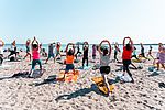 Gruppe macht Yoga am Strand in Schleswig-Holstein bei Sonnenschein – gemeinsames Training mit Blick aufs Meer im Urlaub.