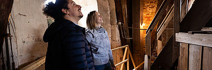 Zwei Personen befinden sich im alten, hölzernen Treppenhaus des Turms der Vicelinkirche Neumünster.  - zum Artikel 'Unbekanntes Land zwischen den Küsten'