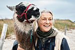Eine Frau nimmt am Strand ein Lama in den Arm.